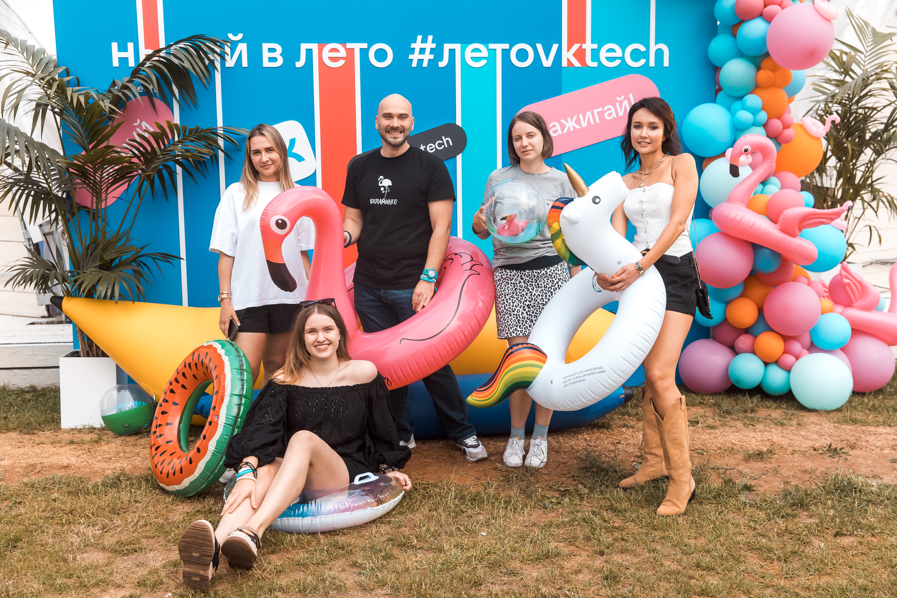 Группа участников корпоративной встречи фотографируется с летним реквизитом